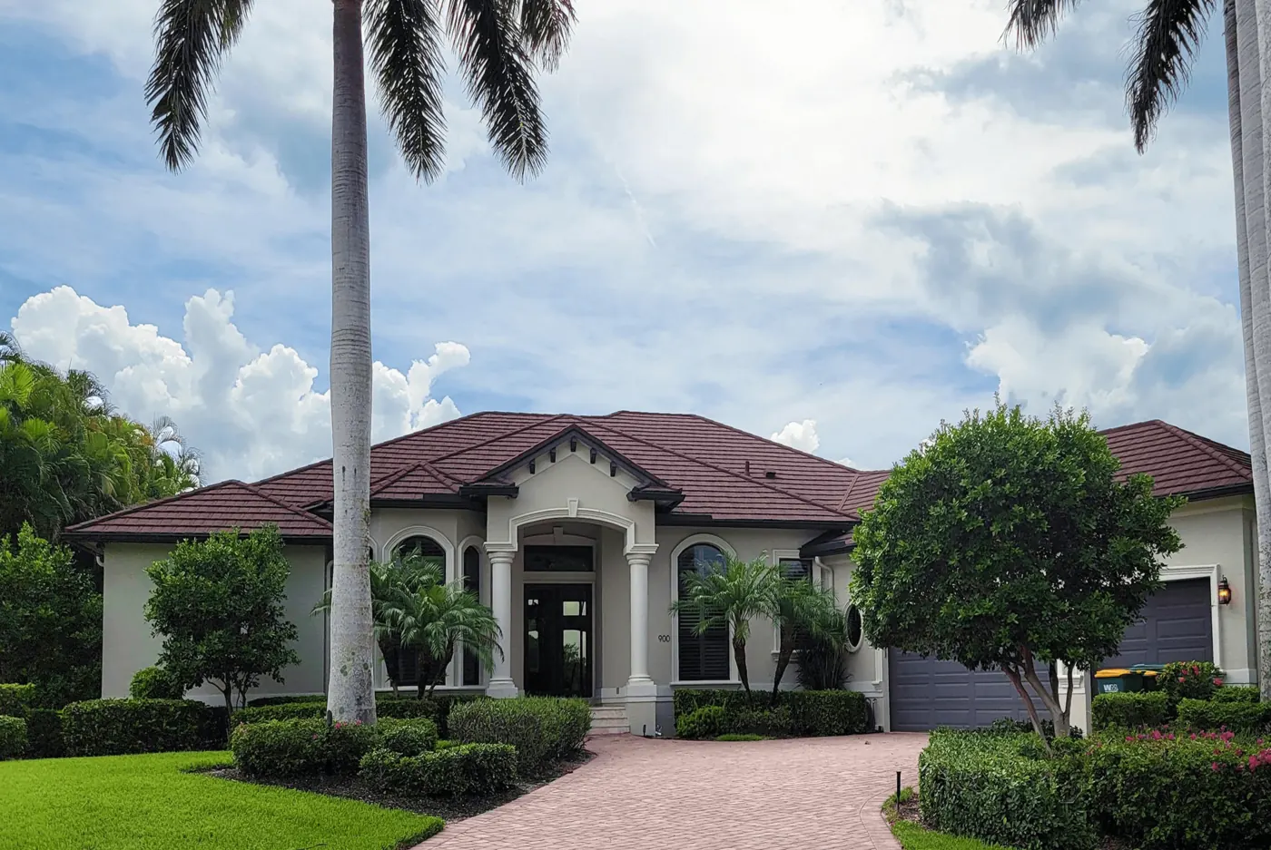 Florida home with new windows and an arched entry framed by palm trees